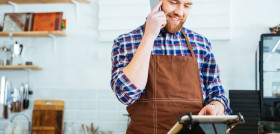 Bearded man holds phone as he looks at POS