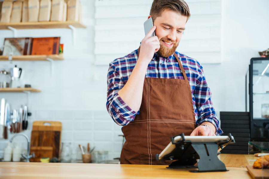 Bearded man holds phone as he looks at POS